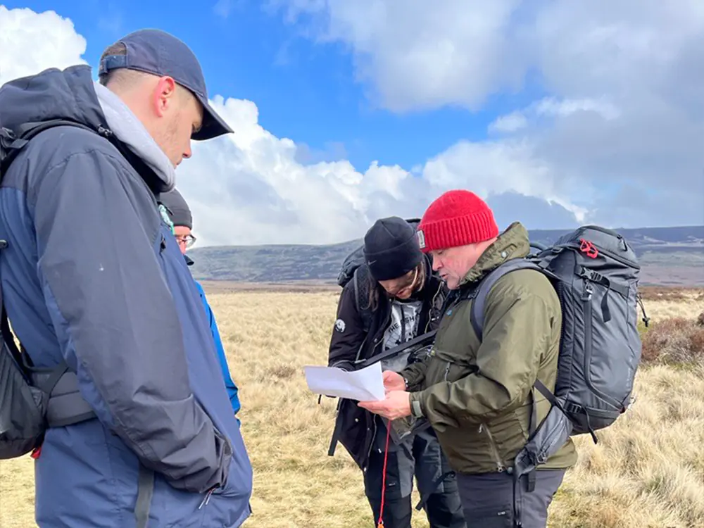 Three males and one female walker looking at a printed out map in a rural setting