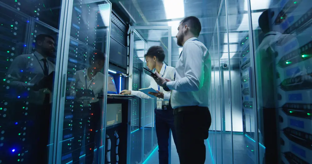 A male and female looking at a laptop which is inbuilt within a data centre rack