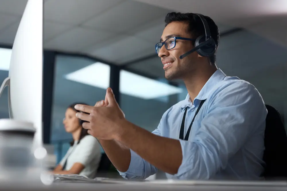 Smiling male in front of monitor providing phone support