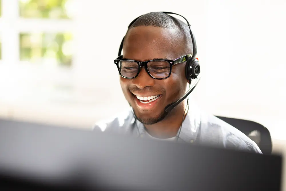 Smiling male in front of monitor providing phone support