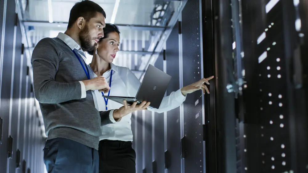 Two colleagues stood with a laptop in a data centre