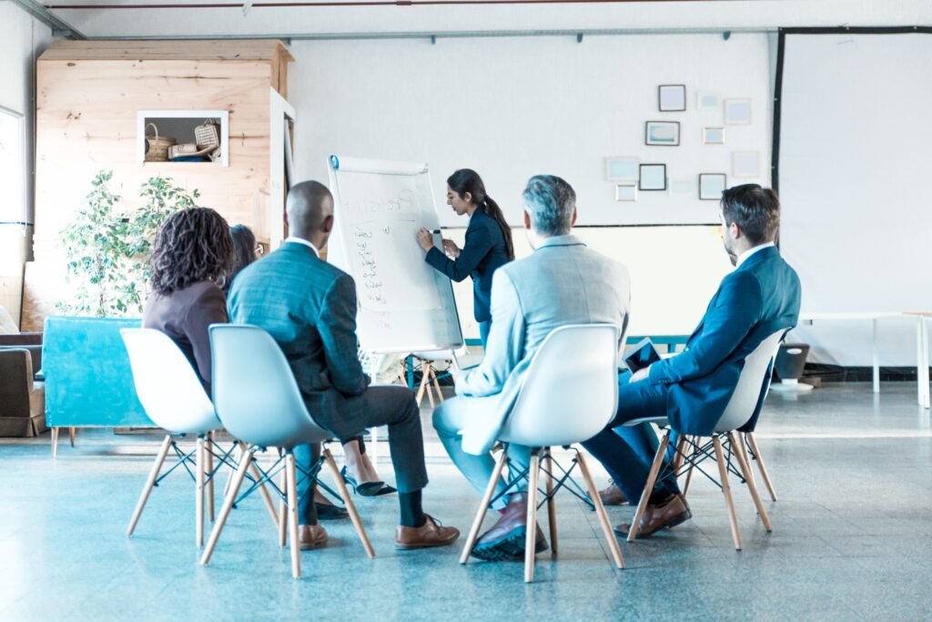 Woman presenting findings on whiteboard to colleagues