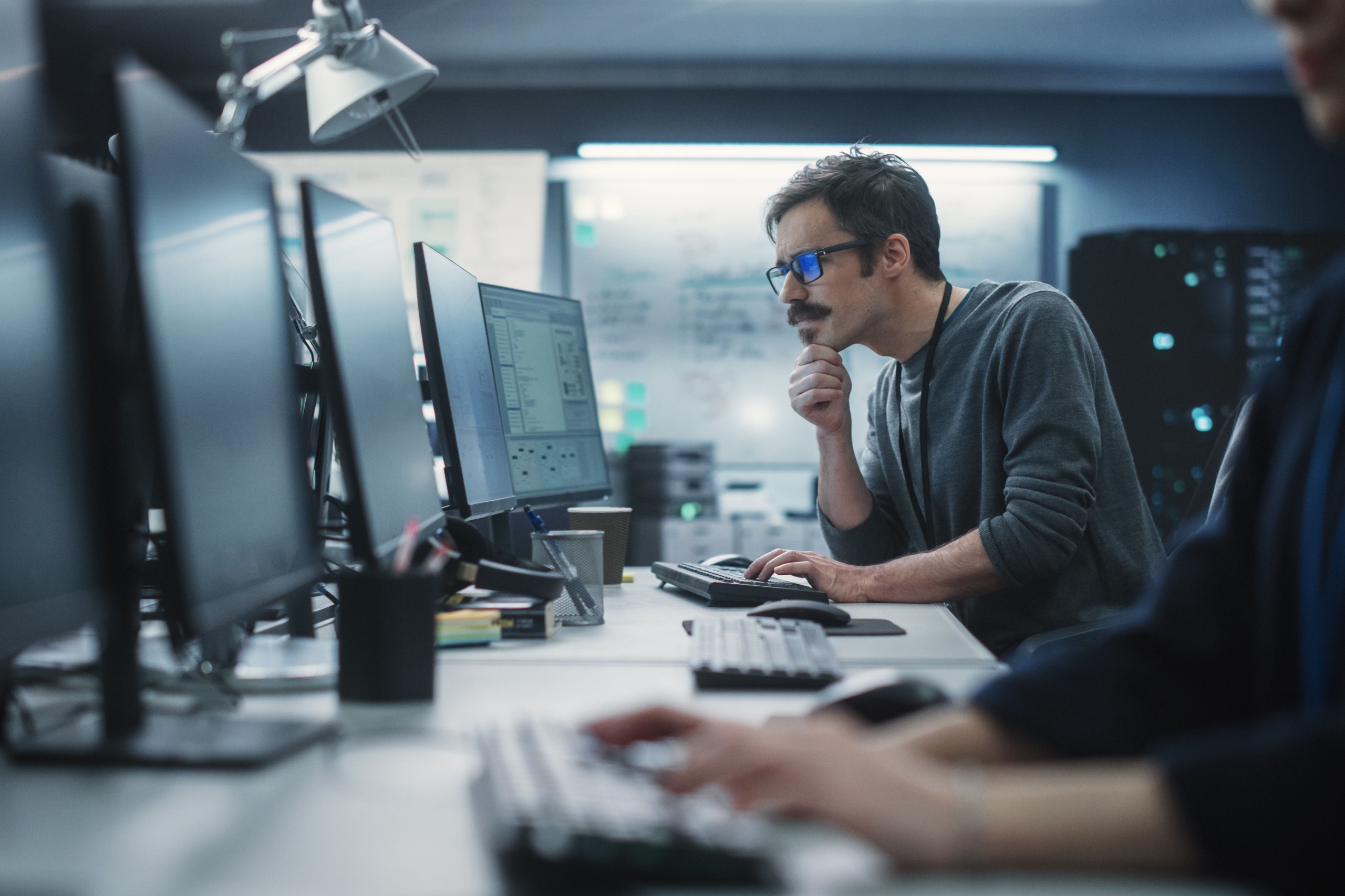 IT engineer looking at a monitor thoughtfully
