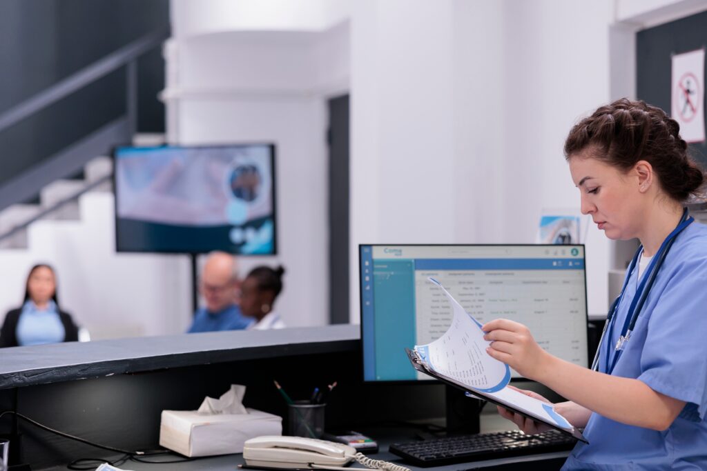 Female healthcare worker looking over documents at a screen