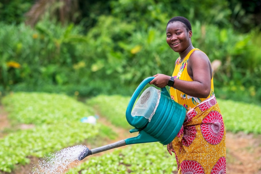 Smiling african woman watering crops