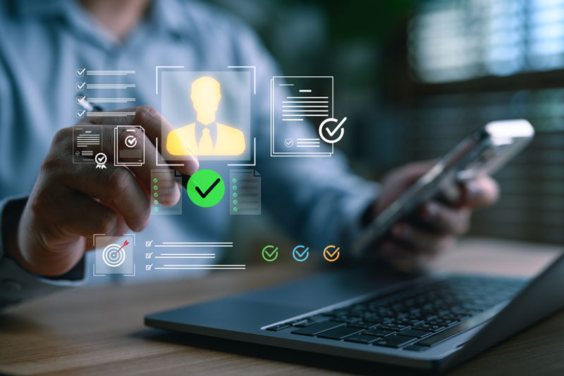 Person at laptop with digital overlay screen with icons and silhouette