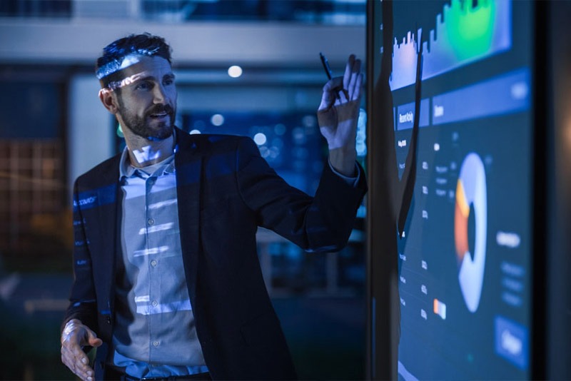 A man stood in front of a projector talking through graphs