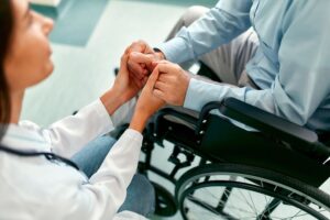 Healthcare professional reassuring man in wheelchair