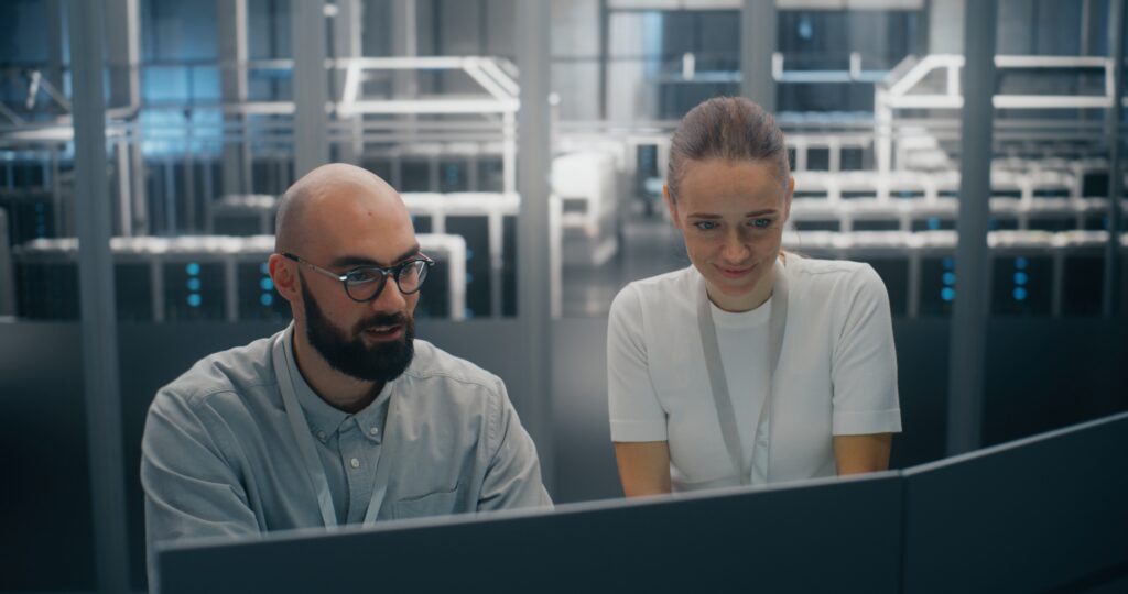 Man and a woman looking at a desktop screen in a data centre environment