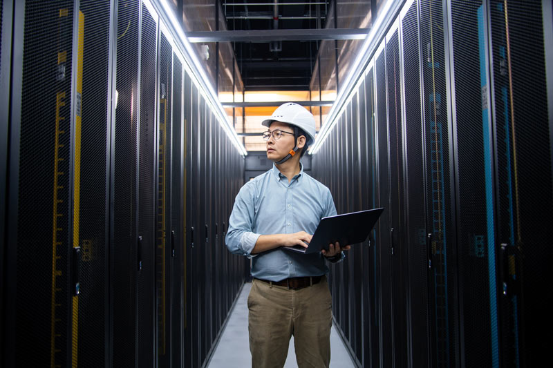 Asian IT engineer in a data centre looking around